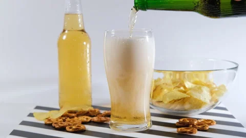 Refreshhing beer poured into glass next to snacks Vídeo Stock 296215355