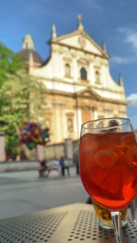 Refreshing Aperol Spritz sits on an outdoor café table with soft-focus views of Stock Footage 337796726