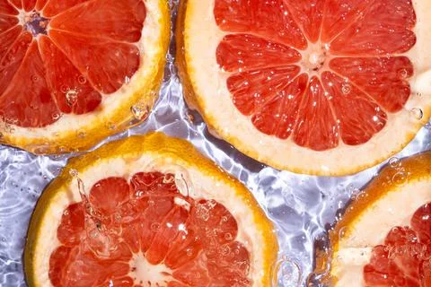 Refreshing background with organic grapefruit in swirling clean water Stock Photos