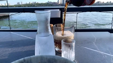 Refreshing Carbonated Beverage Served on a Riverfront Terrace Vídeos de archivo 340052531