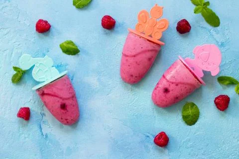 Refreshing children's ice cream popsicles (rasberry sorbet) on blue concrete Foto stock