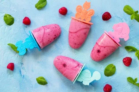 Refreshing children's ice cream popsicles (rasberry sorbet) on blue concrete Stock Photos