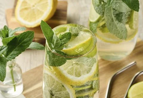Refreshing citrus and mint drink in glasses with ice, lemon, lime, and mint Stock Photos