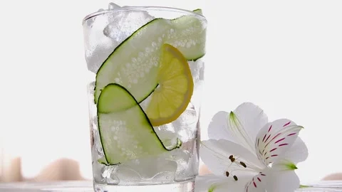 Refreshing  cocktail lemonade with ice, cucumber, lemon pour in glass close up Stock Footage 132134268
