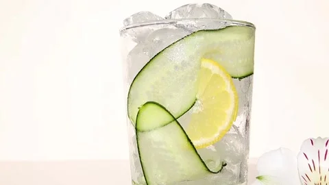 Refreshing cocktail lemonade with ice, cucumber, lemon pour in glass close up Stock Footage 132134281