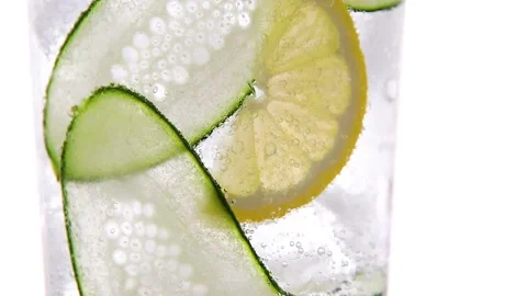Refreshing cocktail lemonade ice, cucumber, lemon, bubbles move in glass closeup Stock Footage 132713356