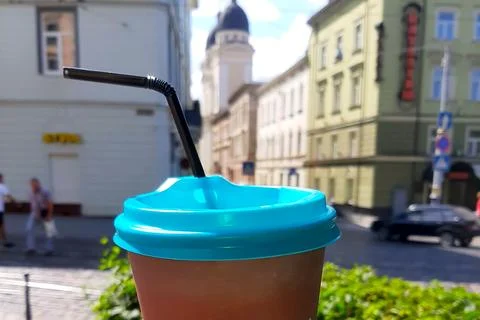 Refreshing Coffee in a Brown Cup With Blue Lid Against a City Summer Backdrop Stock Photos
