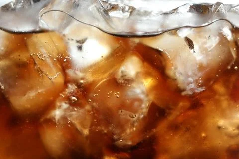 Refreshing cola with ice as background, macro view Stock Photos