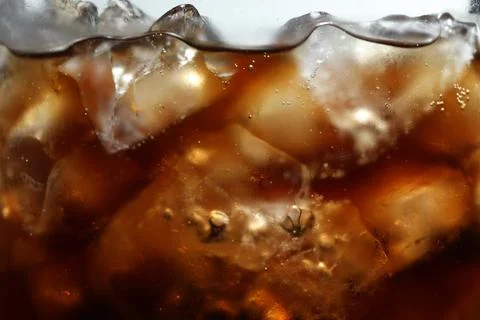 Refreshing cola with ice as background, macro view Stock Photos