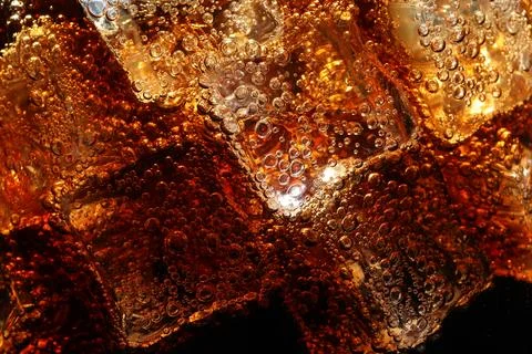 Refreshing cola with ice as background, macro view Stock Photos