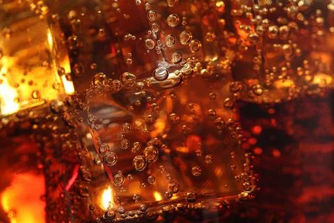 Refreshing cola with ice cubes as background, macro view 스톡 사진