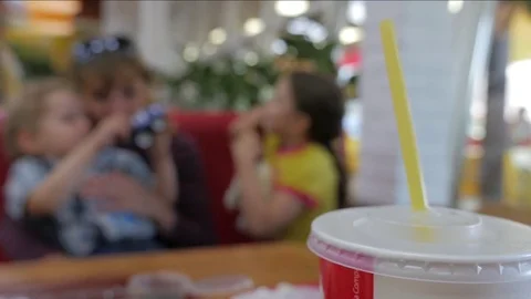 Refreshing cola plastic cup on a table with family people blurred in background. Stock Footage 81564909