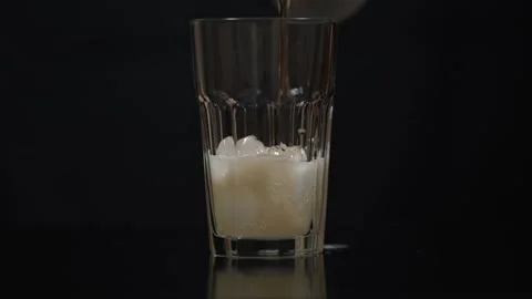 Refreshing cold beer being poured into a clear glass filled with ice cubes Stock Footage 315063180
