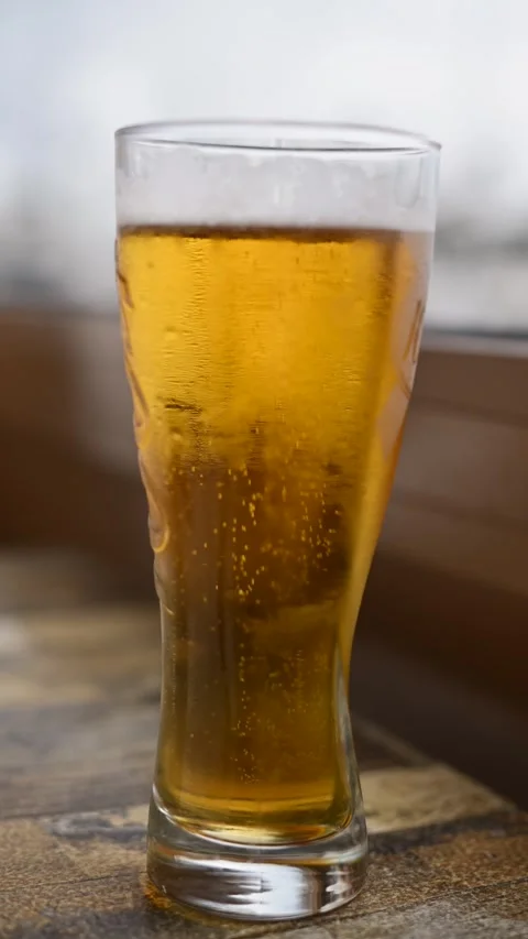 Refreshing cold beer in tall glass with bubbles on wooden table, close up, .. Stock Footage 339409670
