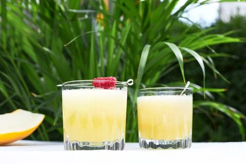 Refreshing cold melon drink with ice and lime slices, garnished with raspberries Stock Photos