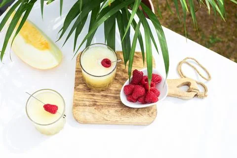Refreshing cold melon drink with ice and lime slices, garnished with raspberries Stock Photos