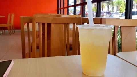 Refreshing Cold Orange Iced Drink in Transparent Plastic Cup on Cafe Table Video stock 320299355