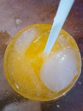 Refreshing cold orange juice served in a glass filled with several large ice Stock Photos