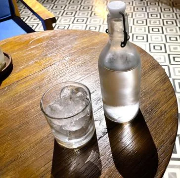 Refreshing cold vodka in the bottle with ice rocks in the glass served in t.. Stock Photos