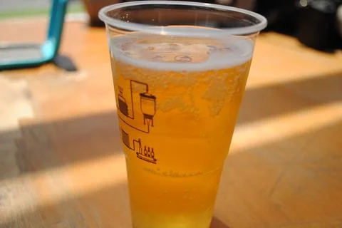 Refreshing craft beer in a plastic cup with brewing process diagram on a wo.. Stock Photos