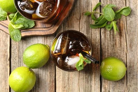 Refreshing Cuba libre cocktail with mint on wooden table, flat lay 스톡 사진