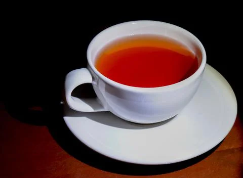 A refreshing cup of black tea, soft lighting, dark wooden floors. Stock Photos