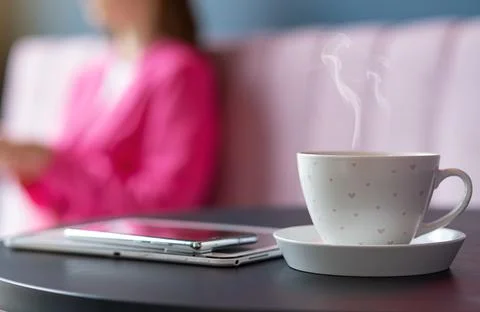 A refreshing cup of hot coffee in a cafe on the background of a freelancer gi Stock Photos