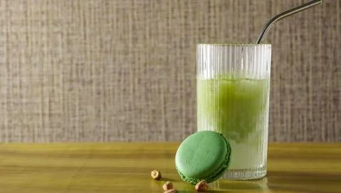 Refreshing drink and green macaron on wooden table Stock Photos