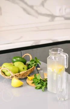 Refreshing drink from citrus and mint in transparent jug on the kitchen table Stock Photos