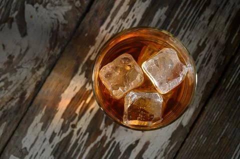 Refreshing drink with ice cubes resting on rustic wooden table in soft afte.. 库存照片