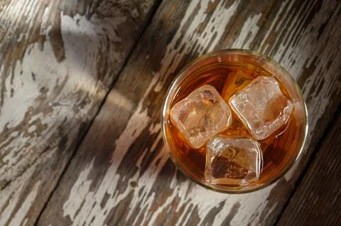 Refreshing drink with ice cubes resting on rustic wooden surface during golde Stock Photos