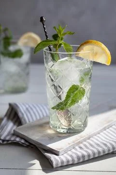 Refreshing drink with lemon and mint in a glass on a white wooden board 写真素材