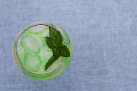 Refreshing drink with mint leaves and ice on a light fabric background 库存照片
