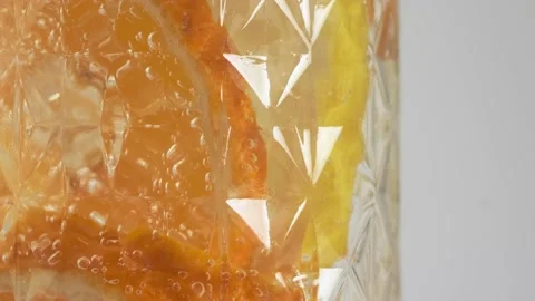 A refreshing drink with slices of lemon and orange in a beautiful faceted glass Video stock 190852680