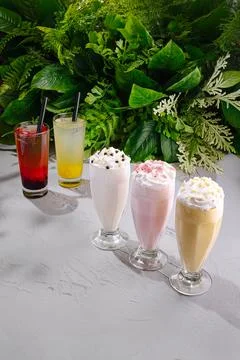 Refreshing drinks in glasses displayed with green plants in the background Stock Photos