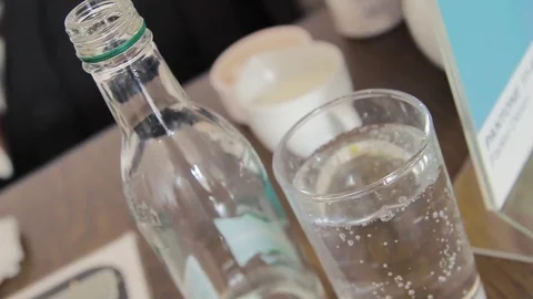 A refreshing empty bottle of water stands next to a fizzing full glass 動画素材 73056622