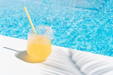 A refreshing fruit juice by the pool in the shade of a palm tree. summer conc Stock Photos