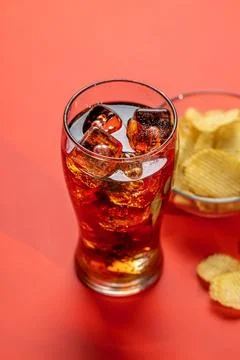Refreshing glass of cola with ice, accompanied by a serving of crispy chips Stock Photos