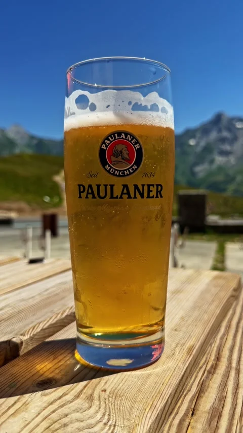 Refreshing glass of cold Paulaner beer sitting on a wooden table in the French Stock Footage 342978657
