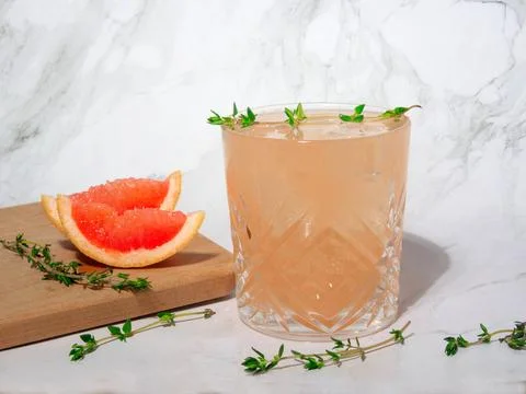Refreshing grapefruit mocktail with ice and thyme on a grey background. Stock Photos