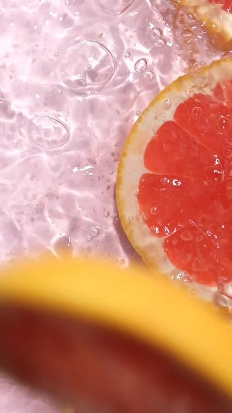 Refreshing grapefruit slice dropping into clear rippling water with a splash, sl Stock Footage 338397274