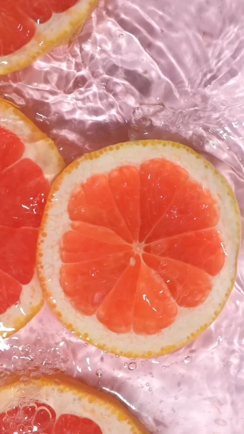 Refreshing grapefruit slice dropping into clear rippling water with a splash, sl Stock Footage 340168066