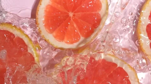 Refreshing grapefruit slice dropping into clear rippling water with a splash, sl Stock Footage 344797359