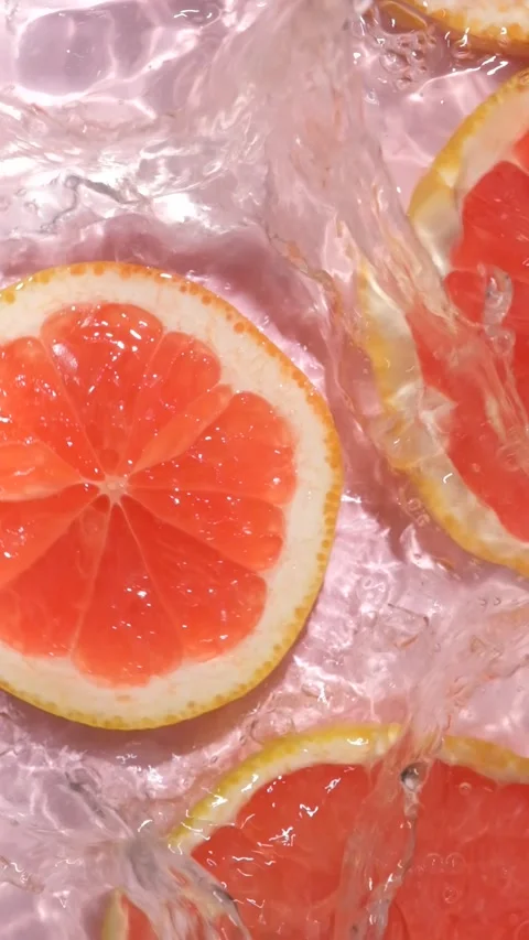Refreshing grapefruit slice dropping into clear rippling water with a splash, sl Stock Footage 345226714