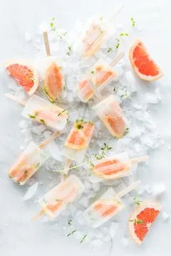 Refreshing grapefruit thyme popsicles scattered around on a bed of ice. Stock Photos