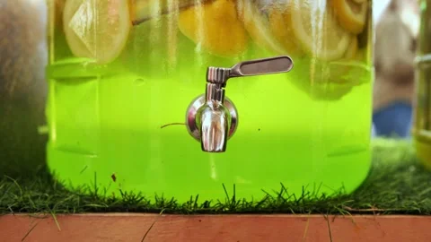 Refreshing green lemonade with lemon slices in beverage dispenser featuring Stock Footage 315746035