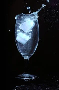 Refreshing ice cubes floating in a clear drink glas Stock Photos
