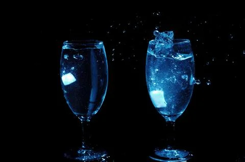 Refreshing ice cubes floating in a clear drink glas Stock Photos