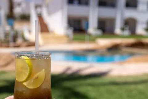 Refreshing iced beverage with lime slices being half by a mans hand beside .. Foto stock
