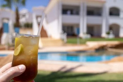 Refreshing iced beverage with lime slices being half by a mans hand beside .. Foto stock